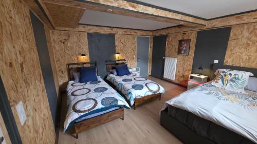 two beds in a room with wooden walls at Chambre d'hôtes MA DAME in Clérey