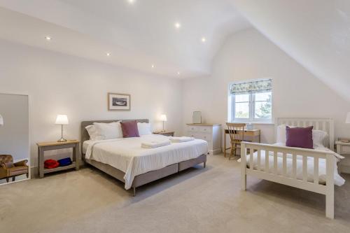 a white bedroom with a bed and a bench at 5 Bed in Walberswick oc-hlwal in Walberswick