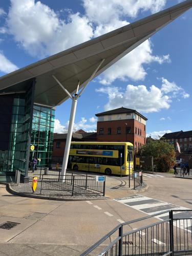a yellow bus parked in front of a building at Double bed room like a hotel room with share toilet in Hyde