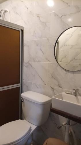 a bathroom with a toilet and a sink and a mirror at Oceans Hostal in Santa Catalina