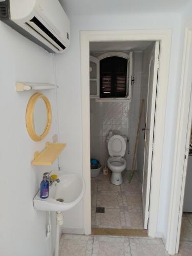 a white bathroom with a toilet and a sink at Studio ANDALOUS in Mahdia