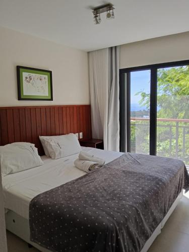 a bedroom with a bed and a large window at Pousada Casa Zoe Búzios in Búzios