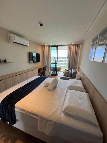 a large white bed in a room with a window at Beach Class Verano - Resort em Muro Alto por Yolo in Ipojuca