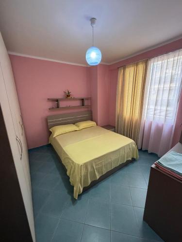 a bedroom with a yellow bed in a pink room at Aldi APARTMENTS in Lezhë