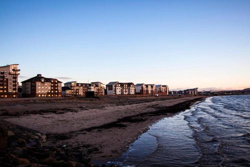 a beach with buildings in the background and the ocean at The Original Donnini Apartment in Ayr