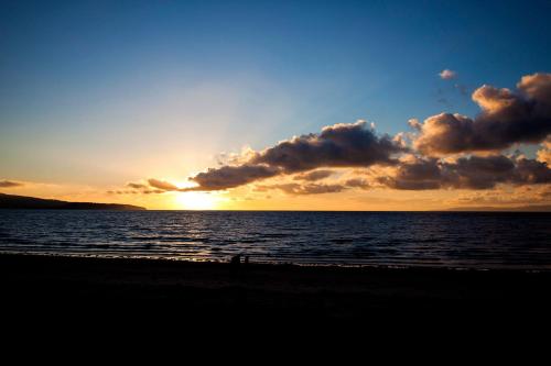 a sunset on the beach with the sun setting at The Original Donnini Apartment in Ayr
