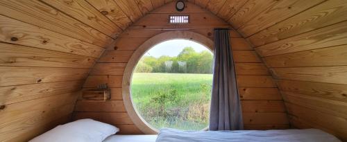 a bedroom with a window in a wooden cabin at Les cabanes du veau in Daumeray