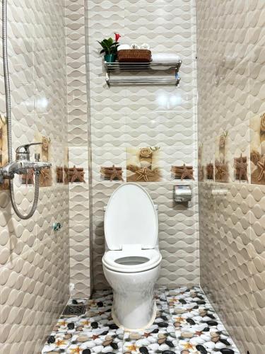 a bathroom with a white toilet and a shower at Palm Lodge in Bố Trạch