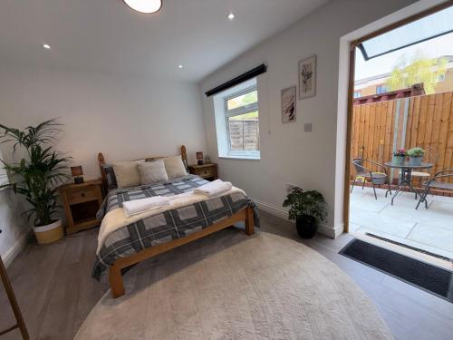 a bedroom with a bed and a balcony with a table at Stylish Apartment with Private Garden Near Victoria Park East London in London
