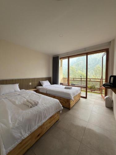 two beds in a bedroom with a large window at HLB Homestay in Ngadisari