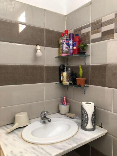 a bathroom counter with a sink and some shelves at Dar Mariem Douz in Douz