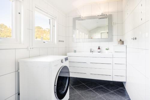 a white bathroom with a washing machine and a mirror at Koselig leilighet strandnær opplevelse! in Grimstad