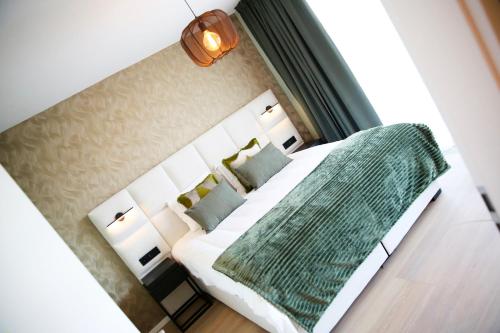 a bedroom with a bed with a green blanket on it at Elite Suite in Liège