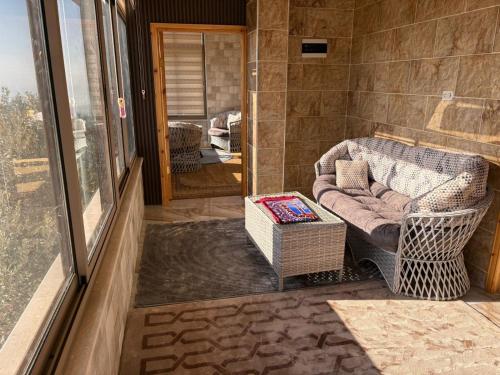 eine überdachte Veranda mit Sofa und Fenster in der Unterkunft Oak Chalet in Umm al Manābī‘