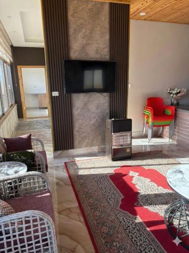 ein Wohnzimmer mit Fernseher und rotem Sessel in der Unterkunft Oak Chalet in Umm al Manābī‘