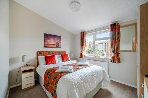 a bedroom with a bed with red pillows and a window at 2 Bed Cabin - Sleeps 4 - Pets - 5 min to Beach in Bridlington