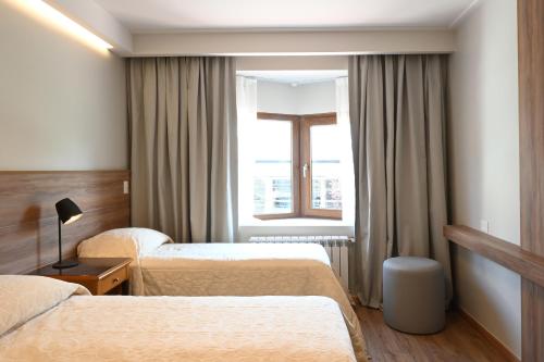 a hotel room with two beds and a window at Hotel Nevada in San Carlos de Bariloche