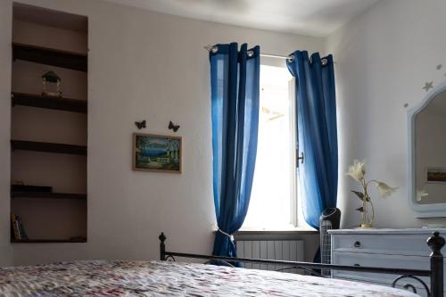 a bedroom with blue curtains and a window at Tuscan retreat in Orciatico