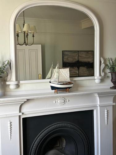 a mirror above a fireplace with a toy boat on it at Barley House, Sea and Beach Facing Accommodation in Southwold