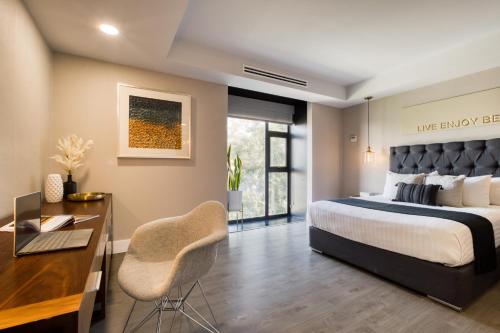 a bedroom with a bed and a desk with a chair at Eazy Rio by ULIV in Tijuana