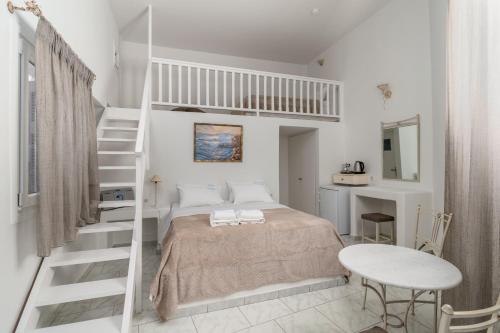 a white bedroom with a bed and a staircase at Livanios Studios in Adamantas