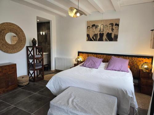 a bedroom with a large white bed with purple pillows at Les Anges de la Vigne par Lisca Begay in Biron