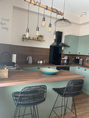 a kitchen with a counter with two chairs and a sink at Warm Spacious apartment in Pembroke Dock