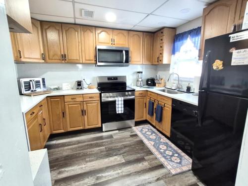 a kitchen with wooden cabinets and a black refrigerator at 3BR St Pete Home Sleeps 6 Private Backyard 15 Min to Beach in St. Petersburg
