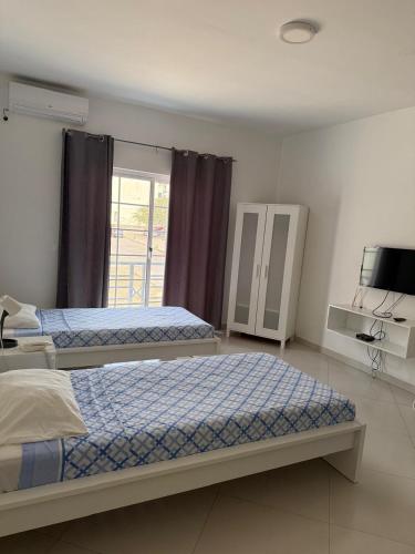 a bedroom with two beds and a tv in it at Urban Praia Maria - ApartHotel in Praia