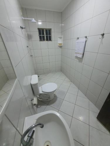 a white bathroom with a toilet and a sink at Casa confortável a 3km do centro in Petrolina