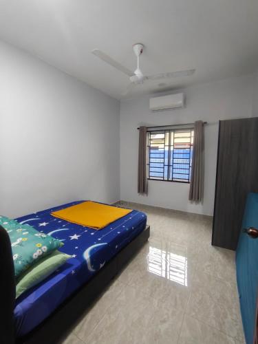 a bedroom with a blue bed in a room with a window at Homestay Ayong in Parit Raja