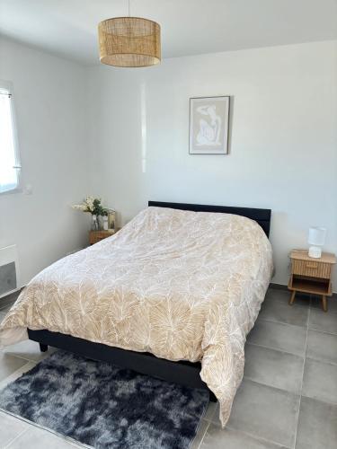 a bedroom with a bed with a comforter on it at Les deux pauses in Martigues