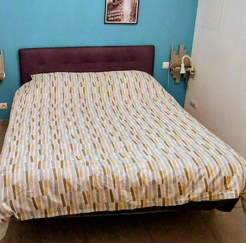 a bed with a striped comforter in a bedroom at gîte en rdc A 200 m tgv et de la fac A 400 m des places 250 places de parking face au logement in Arras