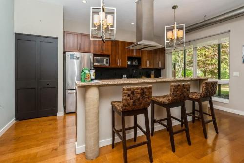 a kitchen with a bar with stools and a refrigerator at The Vineyard Loft in Harbert
