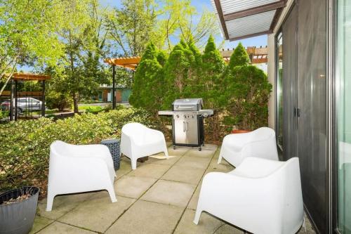 a patio with white chairs and a grill at The Vineyard Loft in Harbert