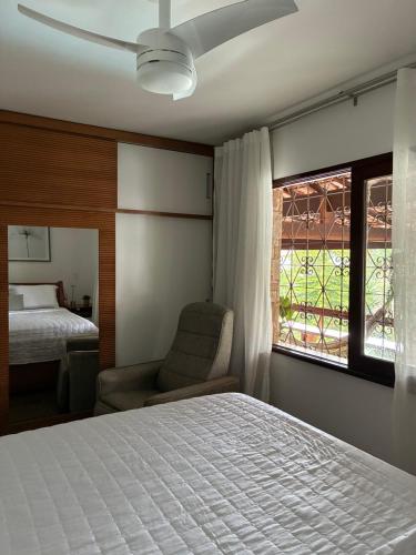 a bedroom with a bed and a chair and a window at Casa Au Clair de Lune Terê in Teresópolis