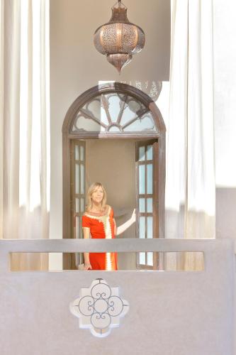 a woman in an orange dress standing in front of a mirror at Riad Palais Bahia Fes in Fès