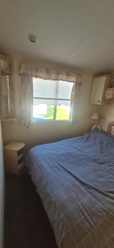 a bedroom with a blue bed and a window at The salsbury lyons robin hood park,rhyl in Meliden