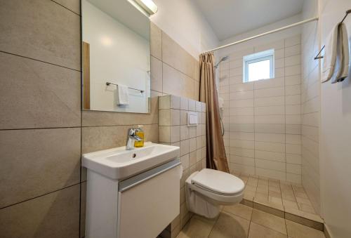 a white bathroom with a toilet and a sink at West Ranga lodge in Hella