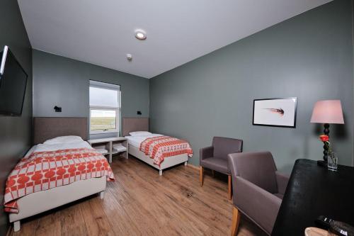 a bedroom with two beds and a chair and a window at West Ranga lodge in Hella
