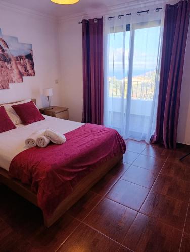 a bedroom with a bed and a large window at Casa de Campo in Caniço