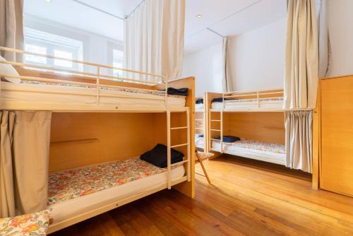 two bunk beds in a room with wooden floors at Porto Lounge Hostel & Guesthouse by Host Wise in Porto
