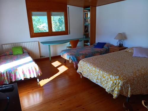 a bedroom with two beds and a table and a window at Torre de l'Olivera in Mediona