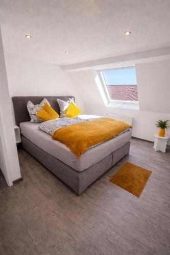 a bedroom with a bed with yellow pillows and a window at Family & Work Apartment in Schopfloch