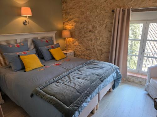 a bedroom with a bed with yellow and blue pillows at Le LOFT GASCON in Mauvezin-dʼArmagnac