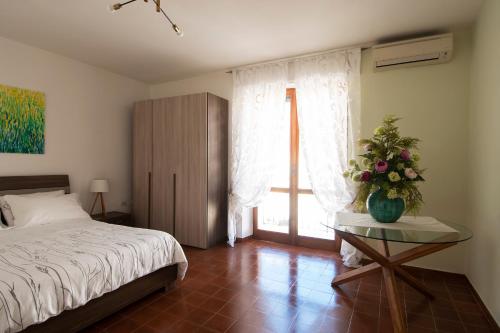 a bedroom with a bed and a table with flowers on it at Anthyllis Apartment in Alghero