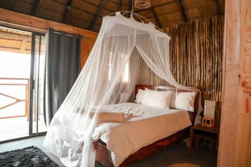 a bed with a canopy in a room with a window at Emms Cubango Ecological Camp in Divundu