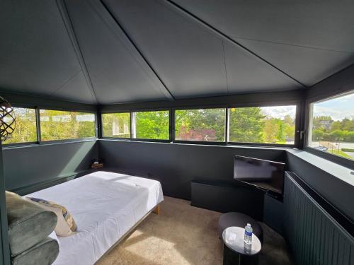 a small room with a bed and windows at Le Castel Guesthouse in Bayeux