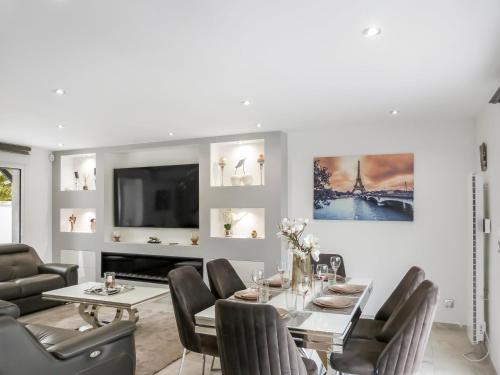 a dining room with a table and chairs and a tv at Grande villa T6 avec piscine à 30 min de Disneyland Paris in Coulommiers