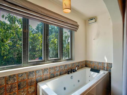 a bath tub in a bathroom with windows at Hotel Pajaros Blu in Calangute